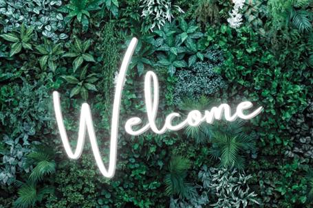 Green foliage with welcome neon sign